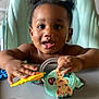 Shëlly participe au concours pour gagner de l'argent avec cette photo : baby, child, colorful, curious, cute, expression, face, hands, happy, high_chair, indoor, infant, person, play, puffy_hair, seat, smiling, toddler, toy, young