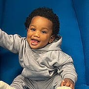 Shëlly participe au concours pour gagner de l'argent avec cette photo : baby, blue_chair, casual_wear, child, comfortable, cozy, curly_hair, cute, feet, gray_clothing, happy, hoodie, indoor, person, portrait, sitting, smiling, sock, toddler, young_child