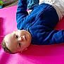baby, child, blue_sweater, pink_mat, toy, indoor, curious, person, infant, playing, cute, lying_down, white_pants, floor, closeup, head, smile, face, young_child, cozy