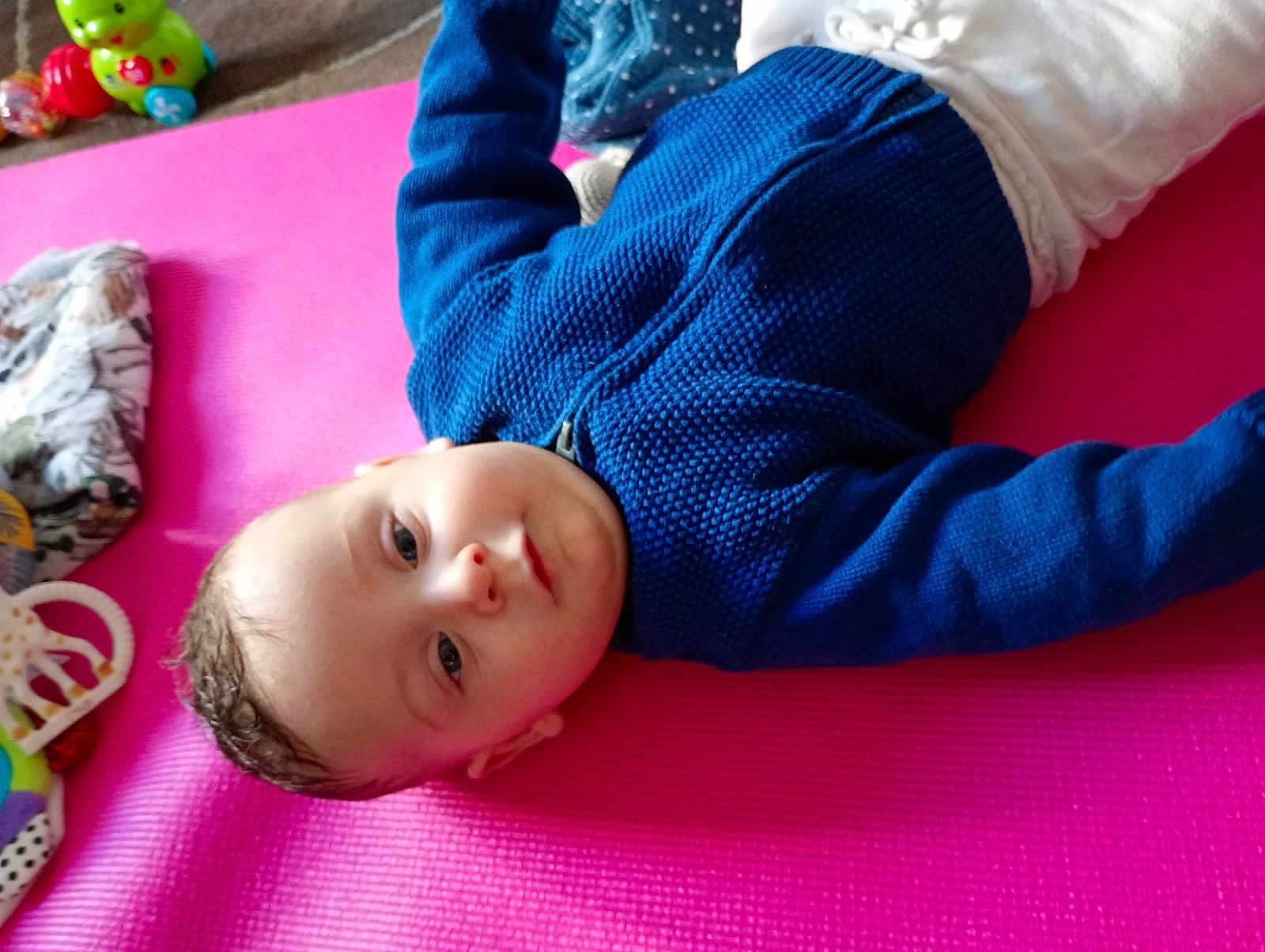 Izaya participe au concours pour gagner de l'argent avec cette photo : baby, child, blue_sweater, pink_mat, toy, indoor, curious, person, infant, playing, cute, lying_down, white_pants, floor, closeup, head, smile, face, young_child, cozy