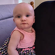 Aurora is registered to the contest to win money with this photo: baby, child, person, face, blue_eyes, pink_top, patterned_skirt, indoor, couch, furniture, holding, portrait, curious, calm, skin, head, shoulder, closeup, colorful, clothing