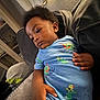 Javaree is registered to the contest to win money with this photo: toddler, child, blue_clothing, couch, indoor, hand, face, curly_hair, relaxed, daylight, portrait, casual, young_child, furniture, home, seated, cute, expression, soft_lighting, cozy
