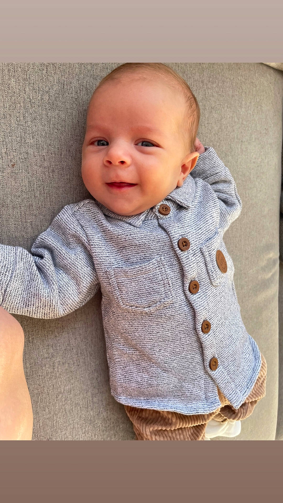 Mayron participe au concours pour gagner de l'argent avec cette photo : baby, button_up, casual_clothing, child, corduroy_pants, cozy, cute, face, gray_sweater, happy, indoors, infant, laying_down, person, portrait, relaxed, smiling, soft_surface, warm_colors, young
