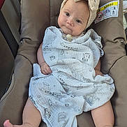 Eïza a rejoint le concours — aidez-le/la à gagner de superbes lots ! baby, infant, child, blanket, headband, bow, seat, cushion, clothing, legs, feet, face, expression, indoors, comfort, pacifier, cute, skin, person, resting
