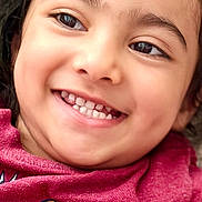 Iknoor is registered to the contest to win money with this photo: cheerful, child, close_up, clothing, colorful, eyes, face, hair, happy, head, indoors, person, photograph, pink_shirt, portrait, selfie, smiling, teeth, toothy_grin, young