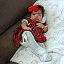 baby, infant, girl, red_bow, plaid_dress, white_tights, blanket, rainbow_pattern, couch, cozy, cute, headband, lace, child, portrait, indoors, sitting, soft, furniture, person