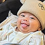 Ammar is registered to the contest to win money with this photo: baby, child, tongue_out, smiling, hat, pom_poms, beige_hat, cozy_clothing, patterned_clothes, indoor, curtain, seat, happy, cute, closeup, infant, playful, face, person, portrait