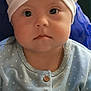baby, child, face, headwrap, white_headwrap, blue_clothing, polka_dot, buttons, portrait, indoor, person, cute, serious_expression, infant, young_child, sitting, closeup, baby_fashion, headwear, baby_girl