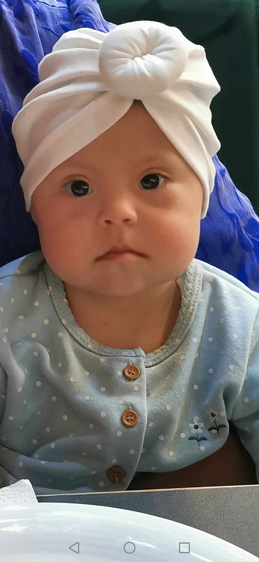 Gulnaz joined the competition — help win amazing prizes! baby, child, face, headwrap, white_headwrap, blue_clothing, polka_dot, buttons, portrait, indoor, person, cute, serious_expression, infant, young_child, sitting, closeup, baby_fashion, headwear, baby_girl