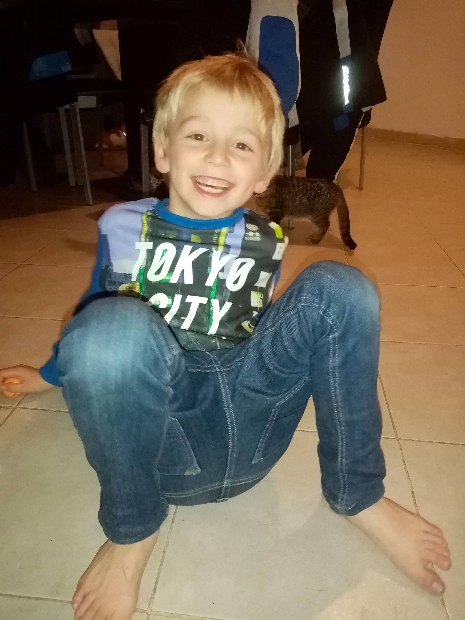 Bryan participe au concours pour gagner de l'argent avec cette photo : barefoot, chair, flash_photography, floor, flooring, fun, hairstyle, happy, head, joint, joy, knee, leg, person, sleeve, smile, sportswear, t_shirt, thigh, toddler