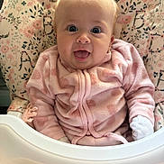 Areleigh is registered to the contest to win money with this photo: apparel, baby, baby_seat, child, cozy, cute, face, floral_pattern, happy, indoor, infant, joyful, onesie, person, pink_clothing, seat, small, smiling, soft_texture, young