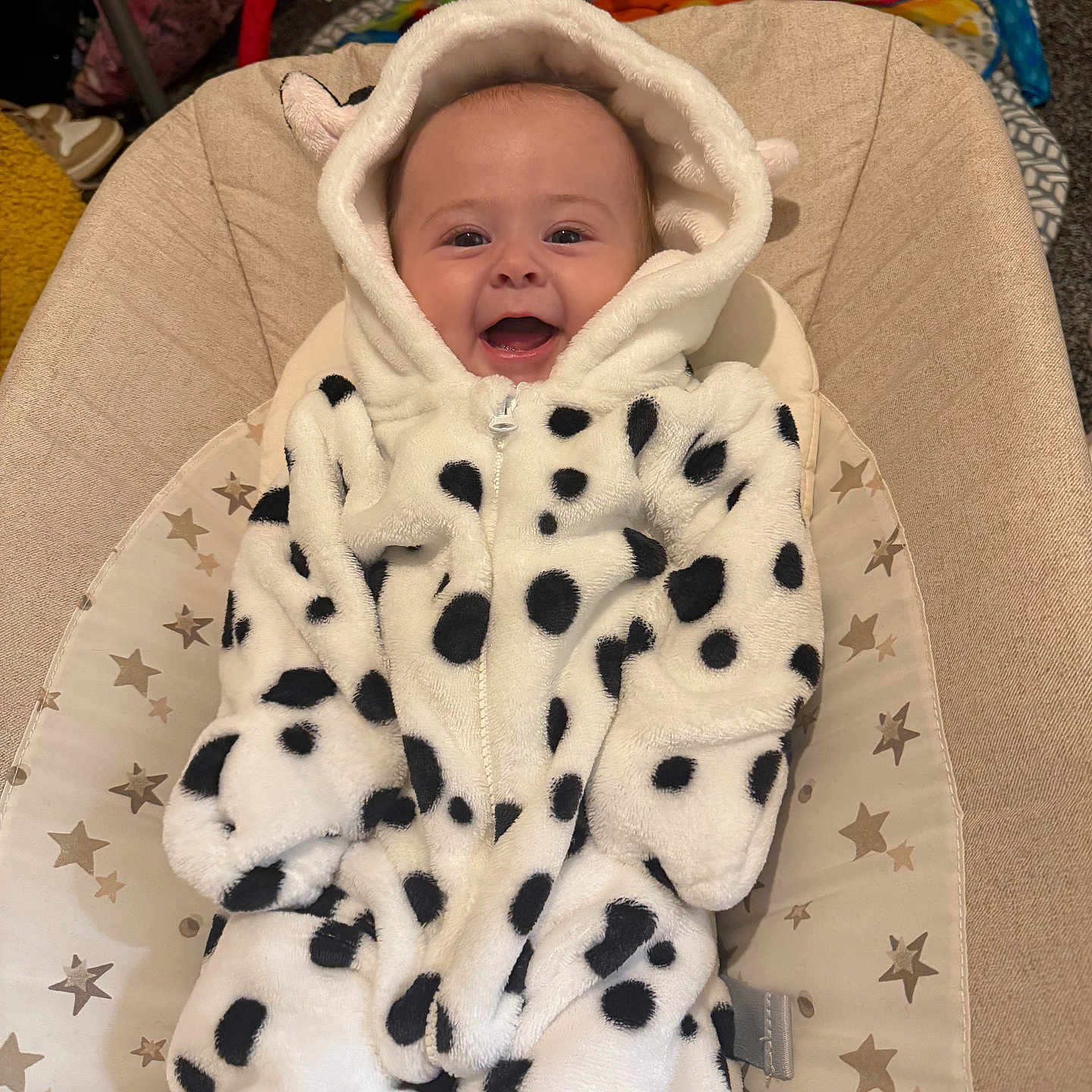 Areleigh is registered to the contest to win money with this photo: baby, baby_seat, carpet, child, clothing, colorful, cute, dalmatian_pattern, face, happy, hood, indoor, infant, onesie, plush, seat, smiling, star_pattern, toy, young_child