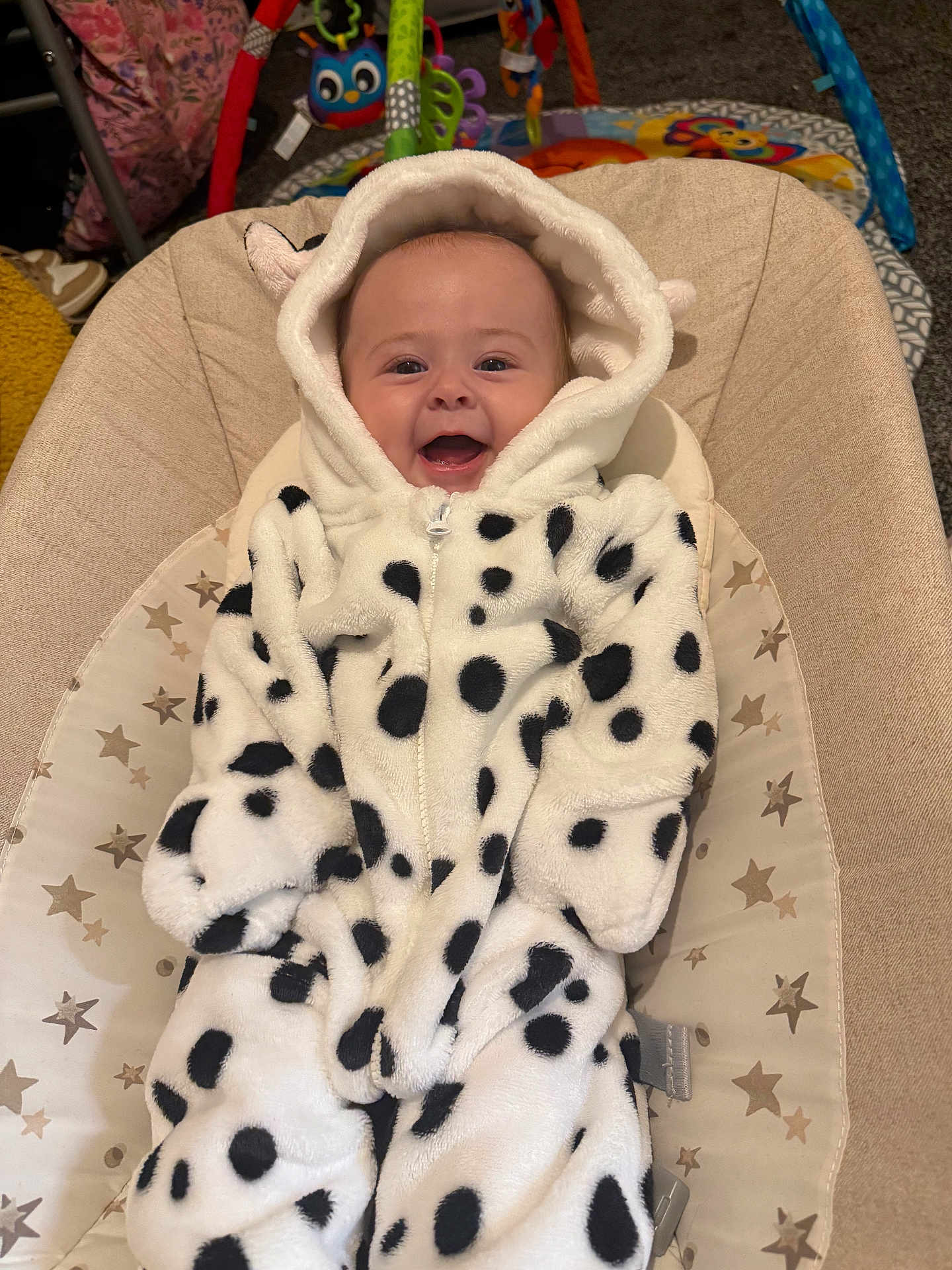 Areleigh is registered to the contest to win money with this photo: baby, baby_seat, carpet, child, clothing, colorful, cute, dalmatian_pattern, face, happy, hood, indoor, infant, onesie, plush, seat, smiling, star_pattern, toy, young_child