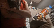 Mocha is registered to the contest to win money with this photo: man, cat, bed, cap, red_shirt, cuddling, bedside_table, lamp, drink_bottle, cans, wallet, pens, indoor, relaxed, cozy, casual, jeans, tattoo, nighttime, intimate