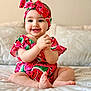 Celine participe au concours pour gagner de l'argent avec cette photo : baby, infant, smiling, clapping, watermelon_print, headband, sitting, bed, soft_fabric, cute, happy, child, portrait, indoors, playful, clothing, person, skin, face, cute_outfit