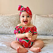 Celine participe au concours pour gagner de l'argent avec cette photo : baby, child, smiling, happy, sitting, bed, pillow, headband, clothing, watermelon_pattern, cute, indoors, portrait, infant, skin, person, feet, hands, face, bright
