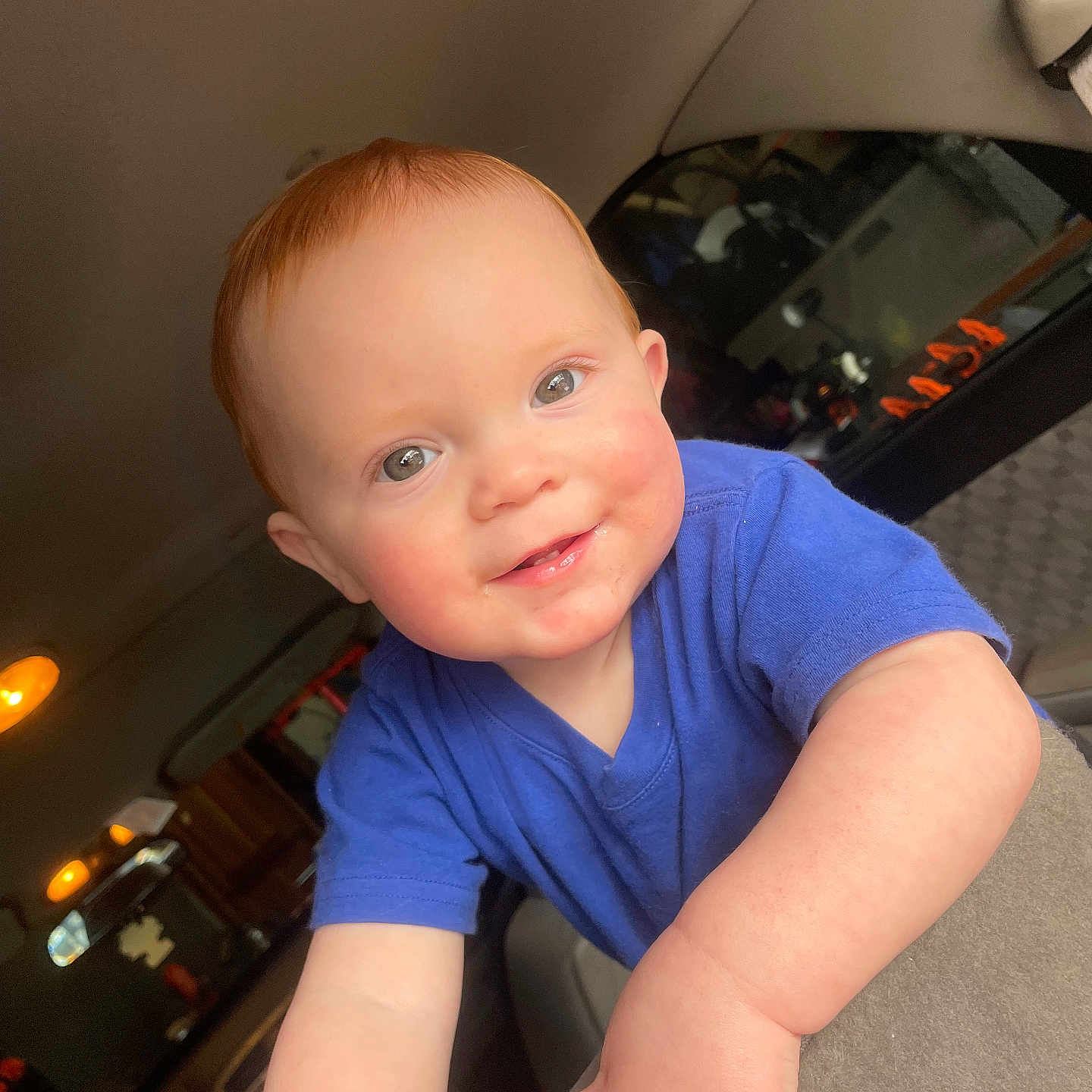 Dominik is registered to the contest to win money with this photo: baby, blue_shirt, candid, car_interior, cheeks, child, close_up, cute, drool, face, hands, infant, light, playful, portrait, red_hair, seat, smile, window, young