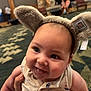 Alessandro is registered to the contest to win money with this photo: baby, child, smiling, animal_ears, headwear, person, indoor, tattoo, watch, hand, clothing, cute, happy, face, infant, lodge, carpet, blurred_background, holding, portrait