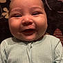baby, smile, onesie, infant, child, face, happy, cheeks, portrait, clothing, fabric, zipper, lying_down, blanket, pattern, floral, soft, cute, head, skin