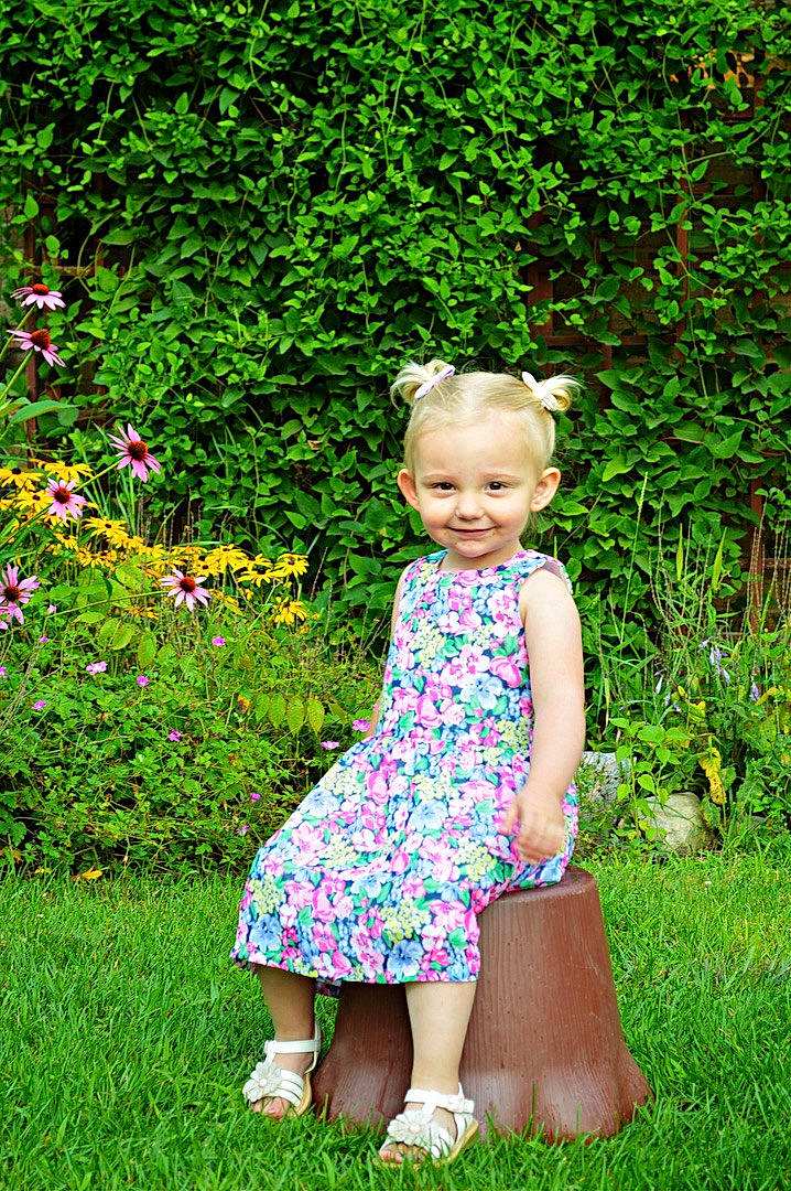 Sadie is registered to the contest to win money with this photo: baby, baby_toddler_clothing, day_dress, flower, grass, grass_family, groundcover, happy, joy, lawn, leaf, magenta, meadow, one_piece_garment, people_in_nature, person, plant, shrub, smile, summer