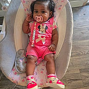 Alaiah joined the competition — help win amazing prizes! adorable, baby, baby_rocker, child, clothing, cute, face, floor, footwear, hair_bow, indoor, infant, pacifier, pacifier_clip, person, pink_clothing, shoes, sitting, toy, wood_floor