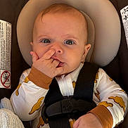 Cash is registered to the contest to win money with this photo: baby, car_seat, infant, child, onesie, face, hand, straps, headrest, clothing, cute, indoors, seatbelt, expression, young_child, sitting, sleeves, pattern, closeup, person