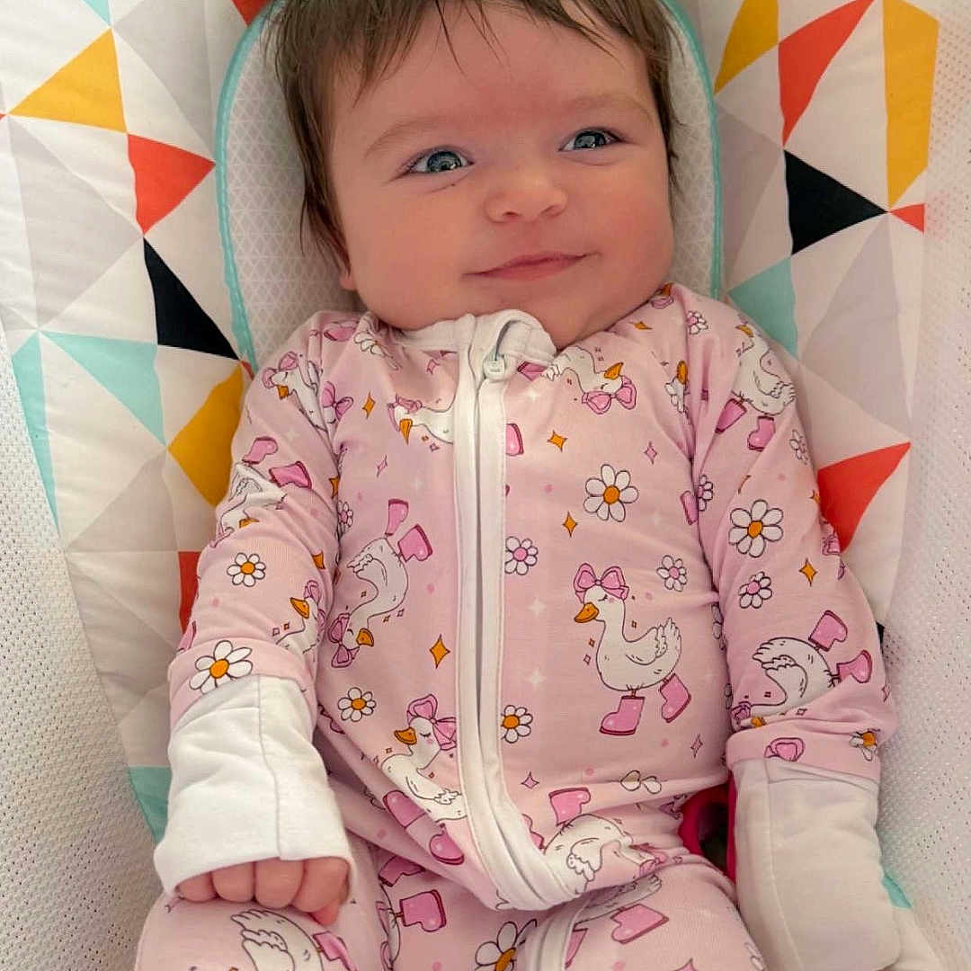 Rosalea joined the competition — help win amazing prizes! baby, blue_eyes, bow, brown_hair, child, close_up, cozy, crib_liner, cute, duck_print, flower_print, geometric_pattern, hand, infant, nursery, onesie, pink_clothing, portrait, sleepwear, smiling