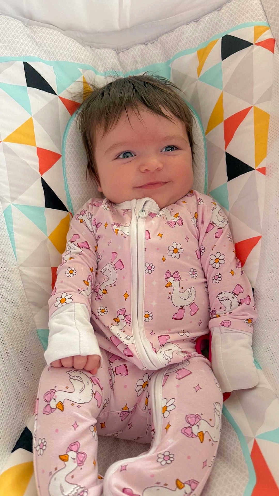 Rosalea joined the competition — help win amazing prizes! baby, infant, onesie, pink_clothing, smiling, blue_eyes, brown_hair, crib_liner, geometric_pattern, duck_print, bow, flower_print, sleepwear, cozy, portrait, close_up, child, hand, cute, nursery
