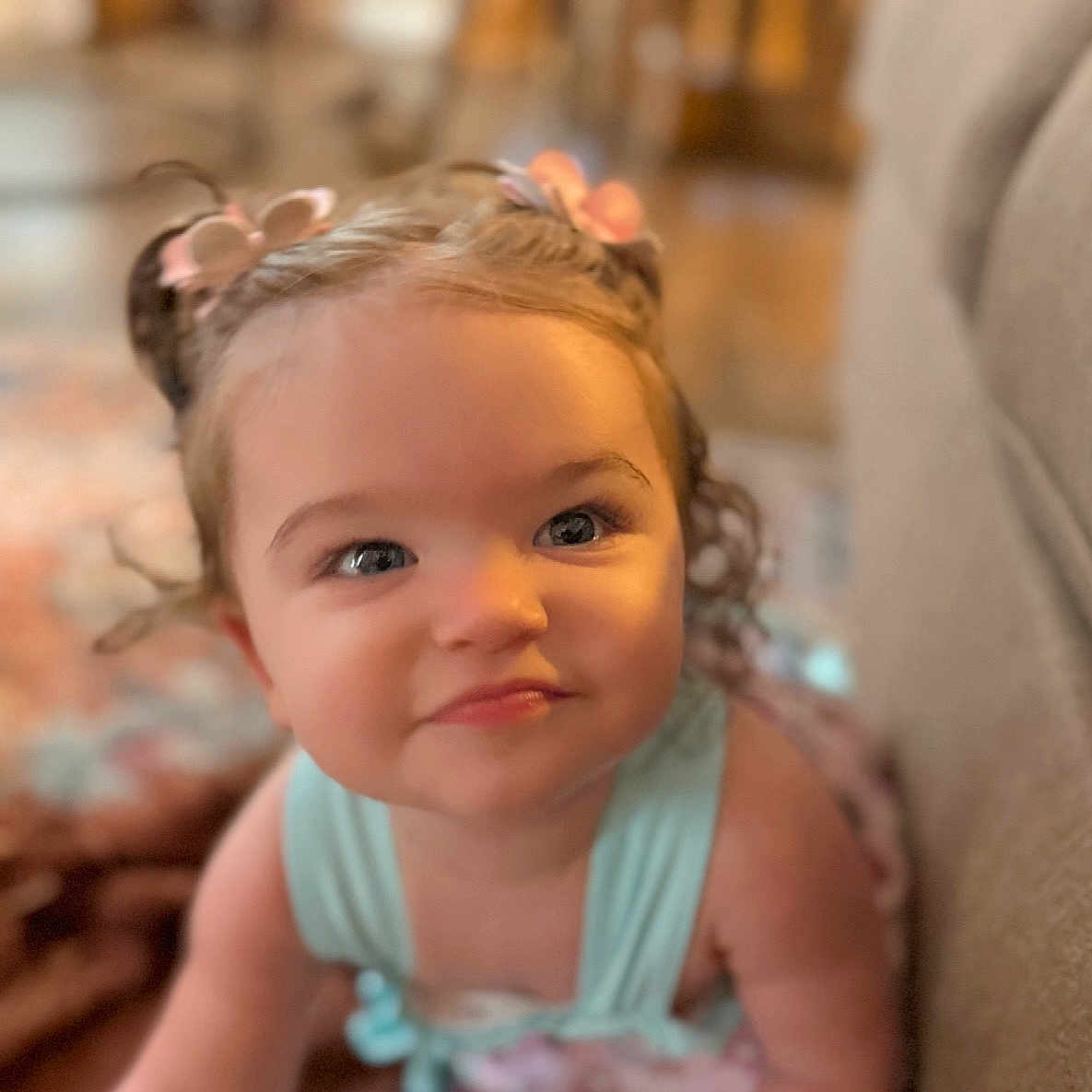 Rosalea joined the competition — help win amazing prizes! baby, child, toddler, portrait, face, eyes, blonde_hair, hair_bows, flower_hair_accessories, sleeveless_top, blue_clothing, sitting, indoors, home, couch, soft_lighting, close_up, looking_at_camera, calm_expression, photography