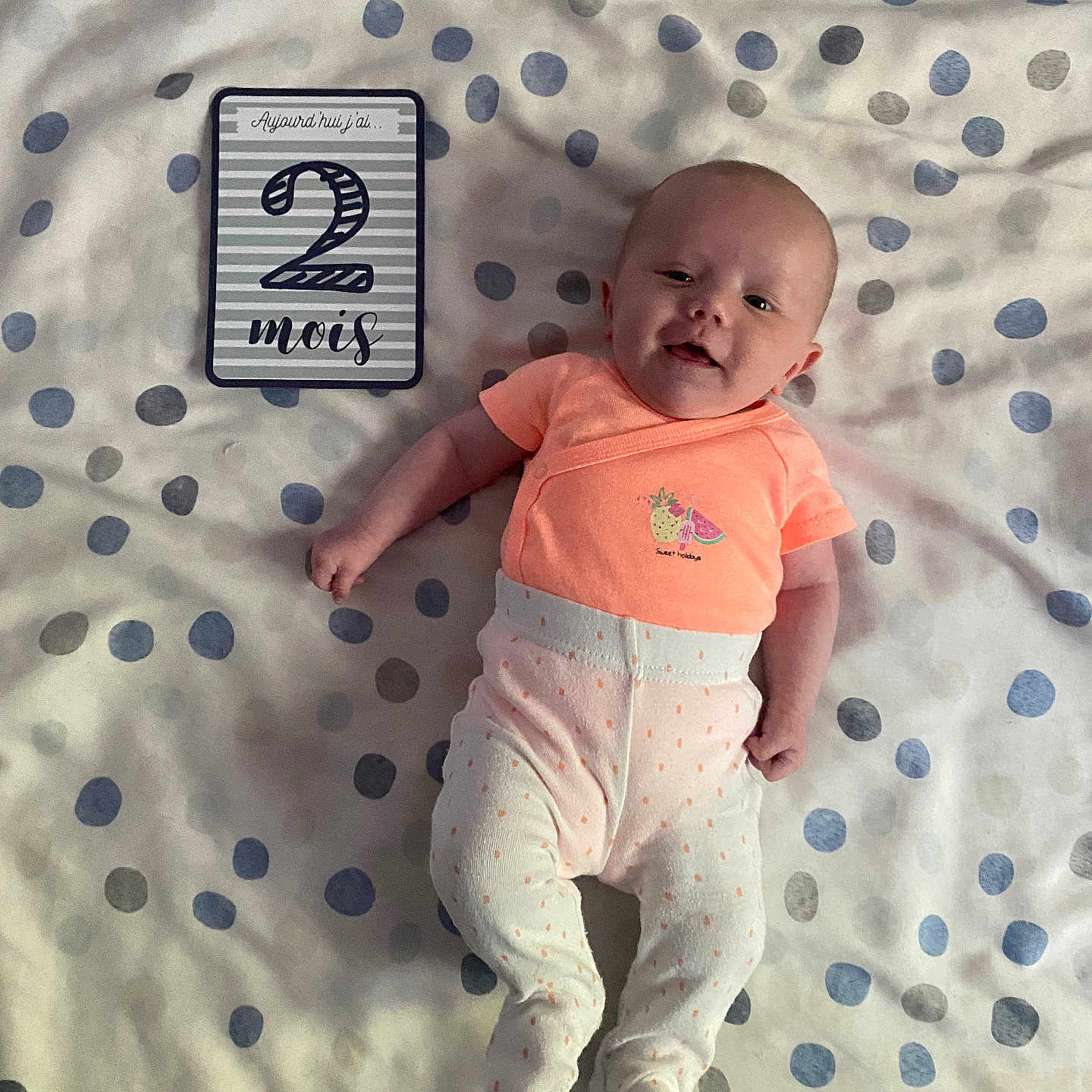 Léna participe au concours pour gagner de l'argent avec cette photo : baby, blanket, celebration, child, clothing, cute, face, happy, indoor, infant, laying_down, milestone_card, newborn, person, pink, polka_dot, portrait, smiling, soft, white