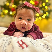 Carla joined the competition — help win amazing prizes! baby, infant, face, headband, bow, sweater, blanket, christmas_tree, bokeh, holiday, indoors, cute, portrait, child, young, lying_down, expression, soft_focus, warm_lighting, festive