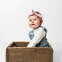 Elizabeth is registered to the contest to win money with this photo: baby, child, clothing, cute, denim_overalls, floor, happy, headband, indoor, infant, light, person, pink_bow, portrait, sitting, smiling, studio, white_background, wooden_box, young