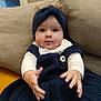 baby, beanie, blanket, bonnet, cap, clothing, couch, cushion, face, furniture, hat, head, homedecor, hood, knitwear, person, photography, portrait, sitting, sweater