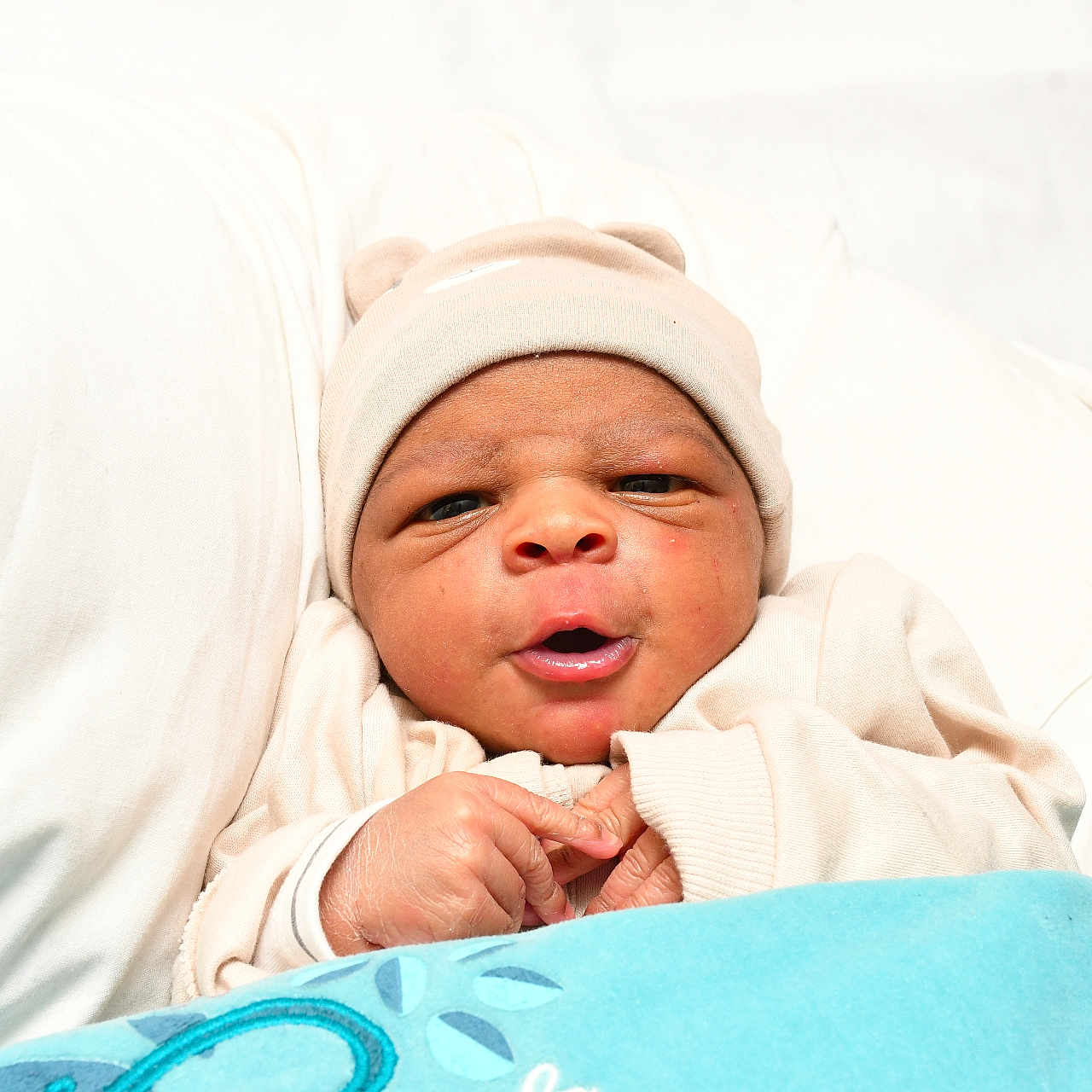 Djihad participe au concours pour gagner de l'argent avec cette photo : baby, infant, newborn, hat, beige_clothing, blanket, blue_blanket, cushion, white_background, face, hands, cute, cozy, portrait, indoors, sleepwear, expression, child, soft, resting