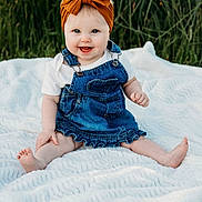 Lenny is registered to the contest to win money with this photo: baby, barefoot, blue_eyes, child, cute, denim, dress, grass, happy, headband, infant, nature, orange, outdoor, person, portrait, sitting, smiling, summer, white_blanket