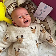 Timothe a rejoint le concours — aidez-le/la à gagner de superbes lots ! baby, infant, smiling, sweater, reindeer_pattern, blanket, plush_toy, milestone_card, lying_down, cute, happy, soft_toys, cozy, child, face, head, person, indoors, warm_light, clothing