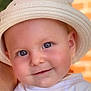 baby, child, face, hat, smile, blue_eyes, skin, white_clothing, closeup, portrait, cheeks, infant, cute, headwear, person, young_child, warm_light, indoors, expression, happy