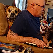 Charlie Alexander joined the competition — help win amazing prizes! bald_man, black_dog, books, brown_dog, chair, couch, cozy, dog, dogs, furniture, glasses, indoors, living_room, man, person, pet, portrait, remote_control, sitting, television