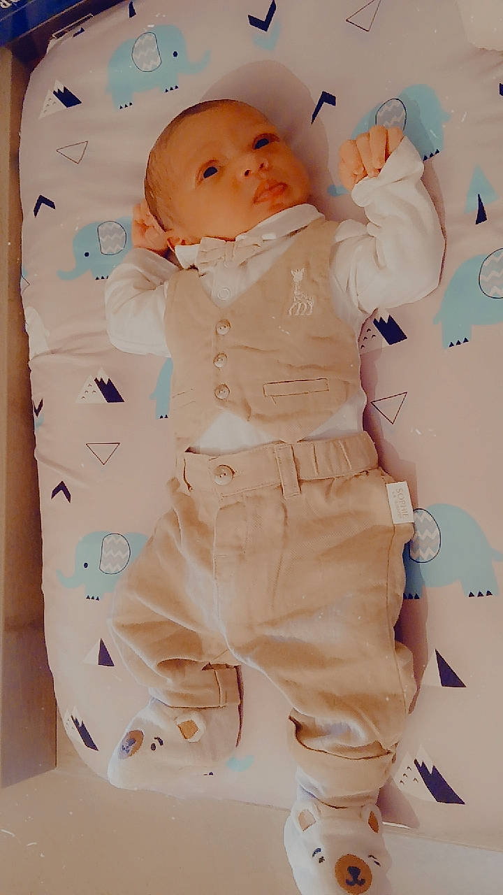 animal_print, baby, bear_socks, bed, child, clothing, cute, elephant_pattern, indoors, infant, lying_down, mattress, newborn, pants, person, portrait, small_hands, socks, soft_lighting, vest