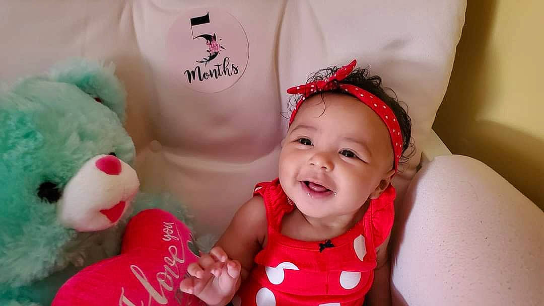 Karma is registered to the contest to win money with this photo: baby, baby_toddler_clothing, beauty, child, dress, event, facial_expression, finger, gesture, happy, headgear, headwear, jewellery, magenta, person, pink, product, red, skin, smile