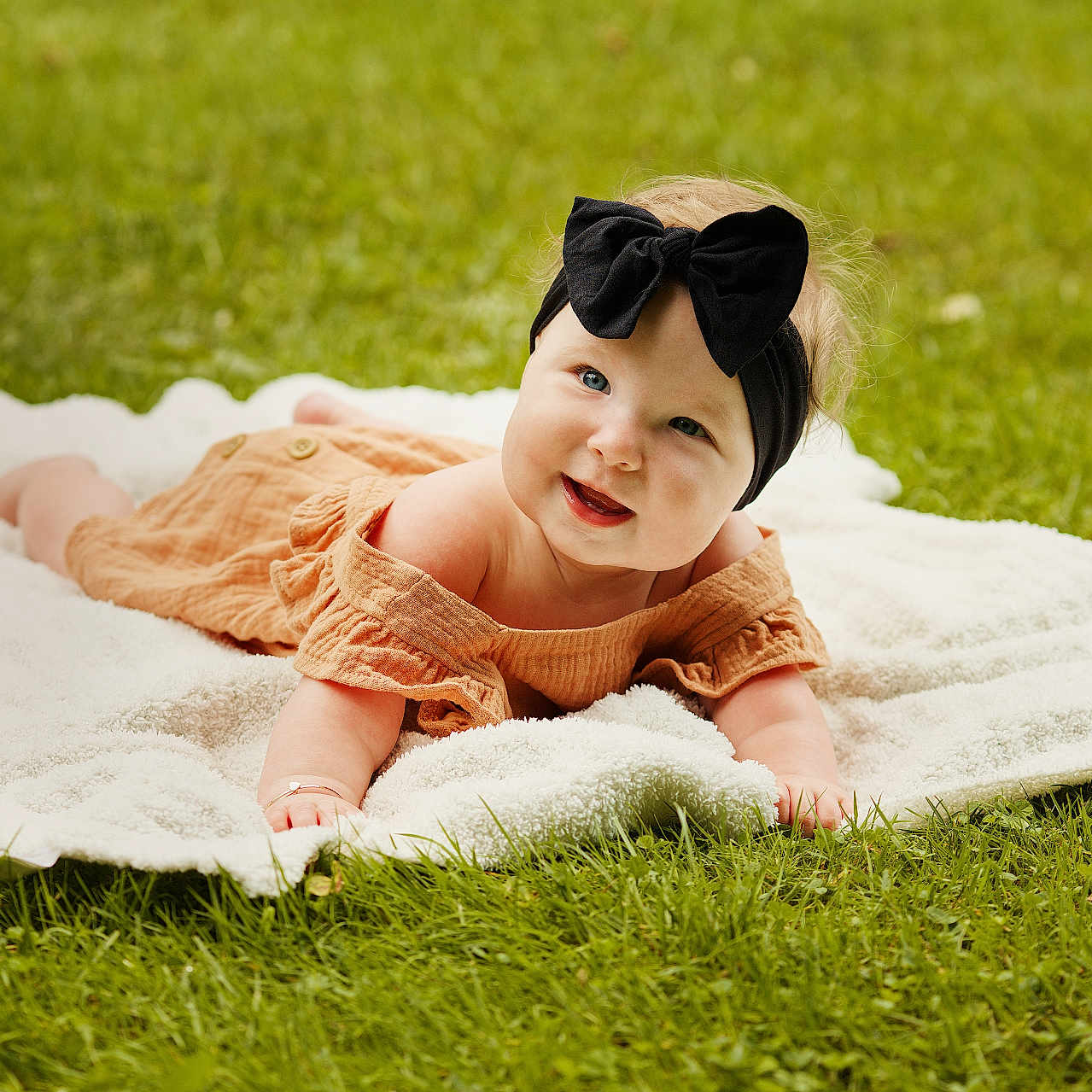 Sophia is registered to the contest to win money with this photo: baby, blanket, bodypart, face, finger, grass, hand, happy, head, laughing, lawn, person, photography, plant, portrait, quilt, smile, summer, sunbathing, towel