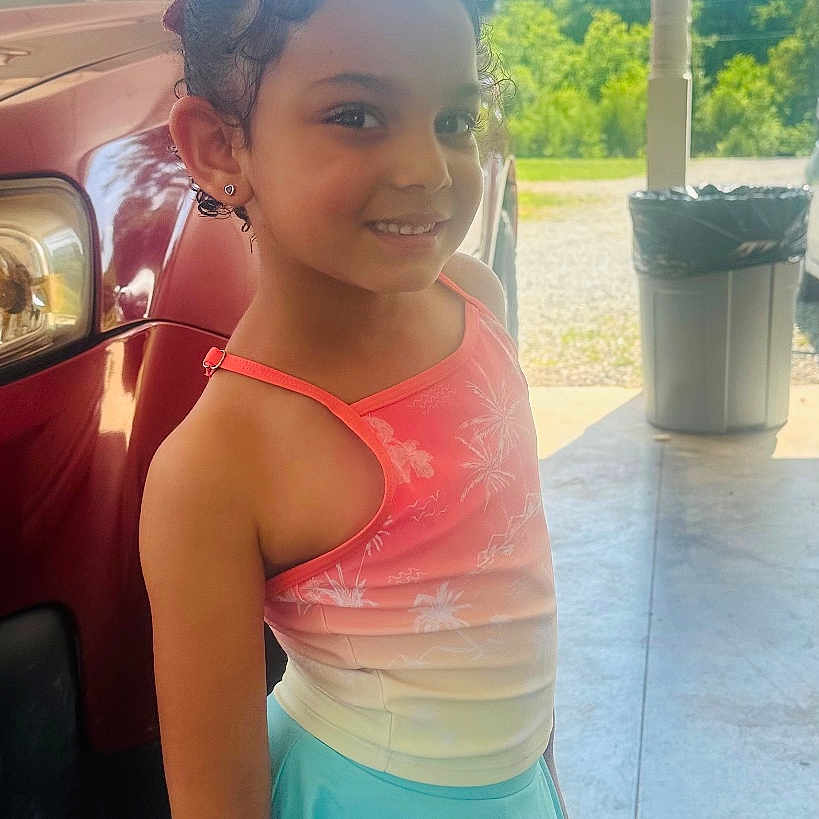 Gracie joined the competition — help win amazing prizes! barefoot, blue_sky, car, child, concrete_floor, daylight, earrings, girl, hair_tied, happy, outdoor, portrait, skirt, smiling, standing, sunny, tank_top, trash_can, trees, vehicle