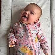 Rosa joined the competition — help win amazing prizes! baby, infant, child, smiling, tongue_out, floral_clothing, onesie, lying_down, changing_pad, patterned_background, animal_drawings, cheeky, cute, happy, pink, yellow, purple, hands, face, head