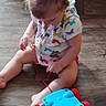 toddler, child, toy, floor, indoor, pull_toy, colorful, curious, sitting, clothing, hair, person, play, wood_floor, red, blue, white, pattern, butterfly, casual
