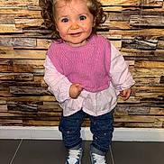 Talya participe au concours pour gagner de l'argent avec cette photo : toddler, child, smiling, curly_hair, blue_bow, pink_vest, blouse, jeans, heart_patches, sneakers, standing, indoor, wooden_wall, floor_tiles, happy, portrait, young_child, fashion, cute, person