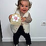 Talya participe au concours pour gagner de l'argent avec cette photo : toddler, child, smiling, standing, holding_sign, indoor, white_wall, curly_hair, leopard_print, vest, black_pants, black_shoes, hair_bow, happy, milestone, sign, floor, portrait, person, cute