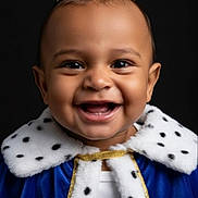 Apollo joined the competition — help win amazing prizes! baby, child, smiling, crown, cape, royalty, blue, fur_trim, portrait, happy, face, headwear, costume, cute, infant, black_background, clothing, jewels, celebration, studio