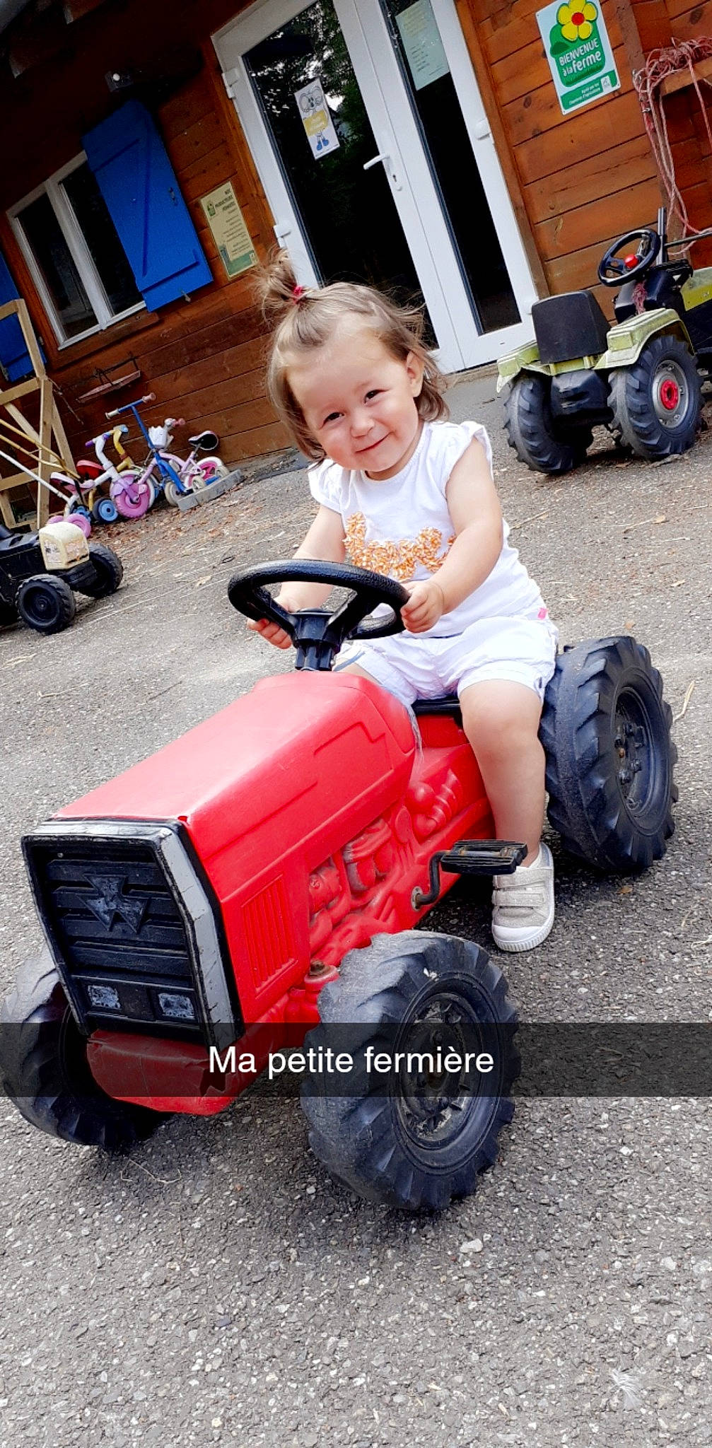 Nina a rejoint le concours — aidez-le/la à gagner de superbes lots ! automotive_design, automotive_tire, automotive_wheel_system, blue, bumper, clothing, fender, joy, mode_of_transport, motor_vehicle, person, riding_toy, shorts, smile, synthetic_rubber, tire, toddler, tractor, tread, vehicle