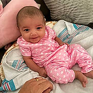 Laniyah is registered to the contest to win money with this photo: baby, child, infant, smiling, portrait, pink_outfit, heart_pattern, onesie, sitting, lying_down, blanket, bed, pillow, stuffed_animal, bunny, adult_hand, indoor, home, happy, cute