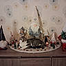 Charlie a rejoint le concours — aidez-le/la à gagner de superbes lots ! cat, tabby_cat, gnome, holiday_decorations, christmas_trees, miniature_figures, pinecones, wooden_furniture, patterned_wallpaper, indoor, decorative, festive, relaxed_cat, ornaments, stuffed_toys, tabletop, seasonal, cozy, home_decor, animal